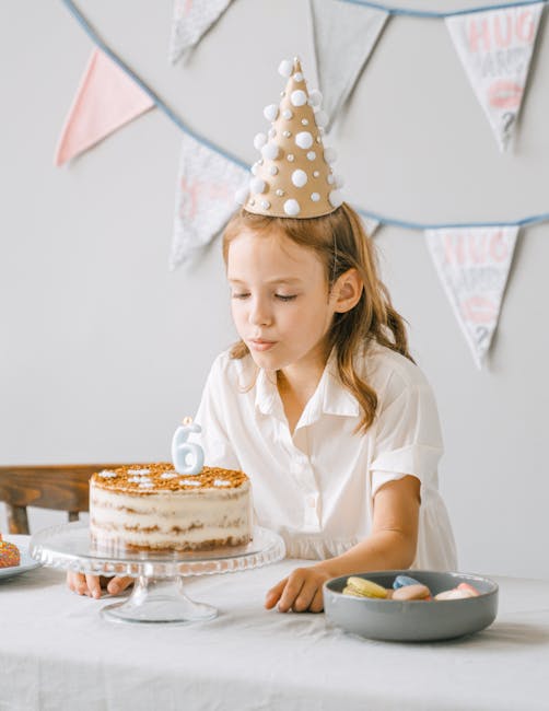 Young girl blowing out a birthday candle shaped as number 6